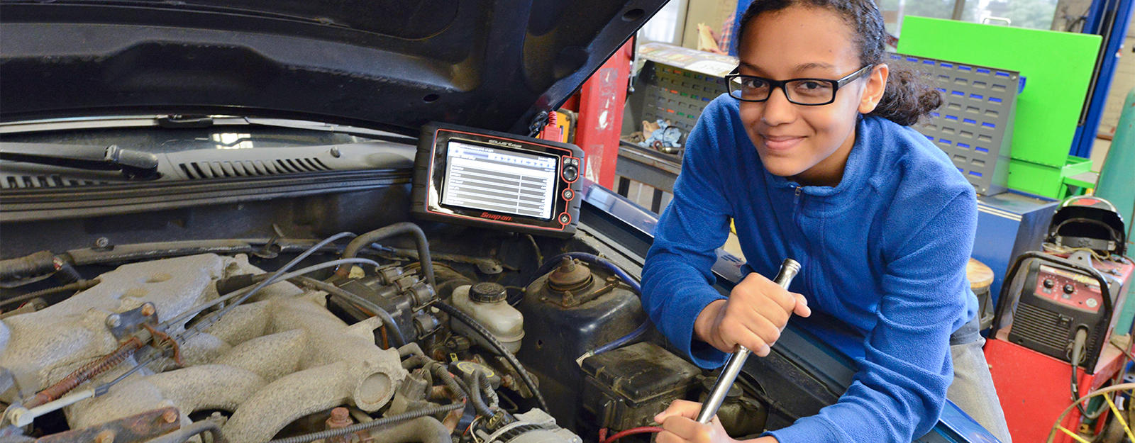 Student working on the engine of a car.